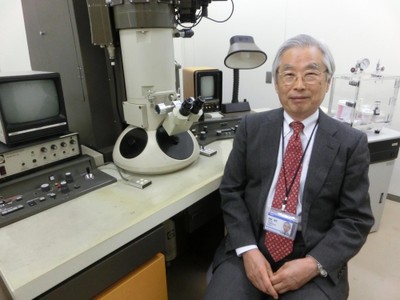 カーボンナノチューブを発見した電子顕微鏡の前で(提供：NEC）