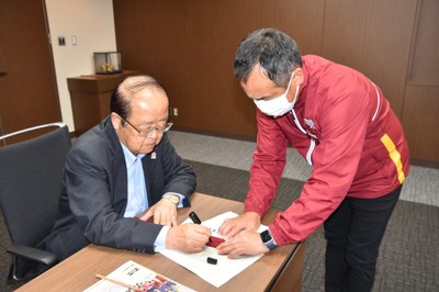 たすきにメッセージを書く立花理事長