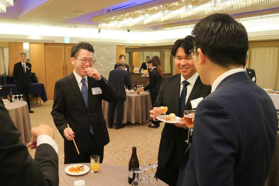 △ 立食形式の会場で食事を囲みながら会話を交わす様子