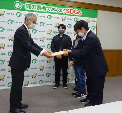 寄付金と目録を手渡す