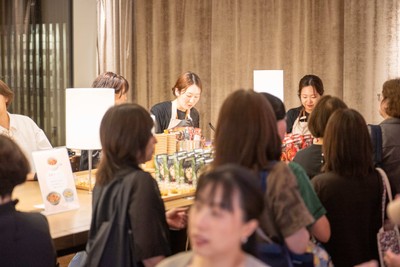 試食テーブルに集まる来場者と、料理を提供するスタッフ