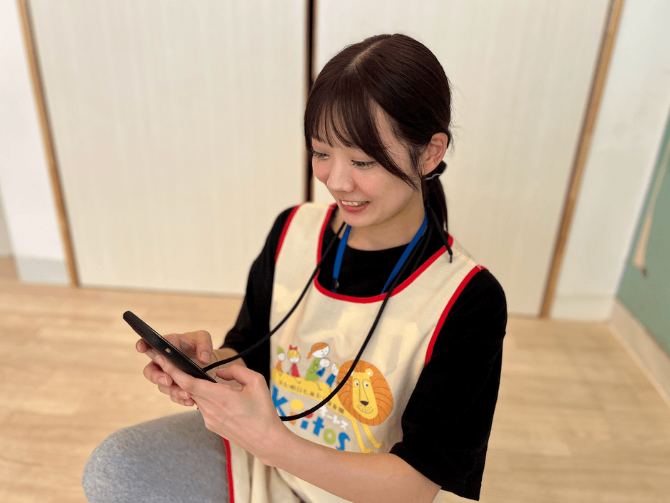スマートフォンで園児情報を確認する保育士
