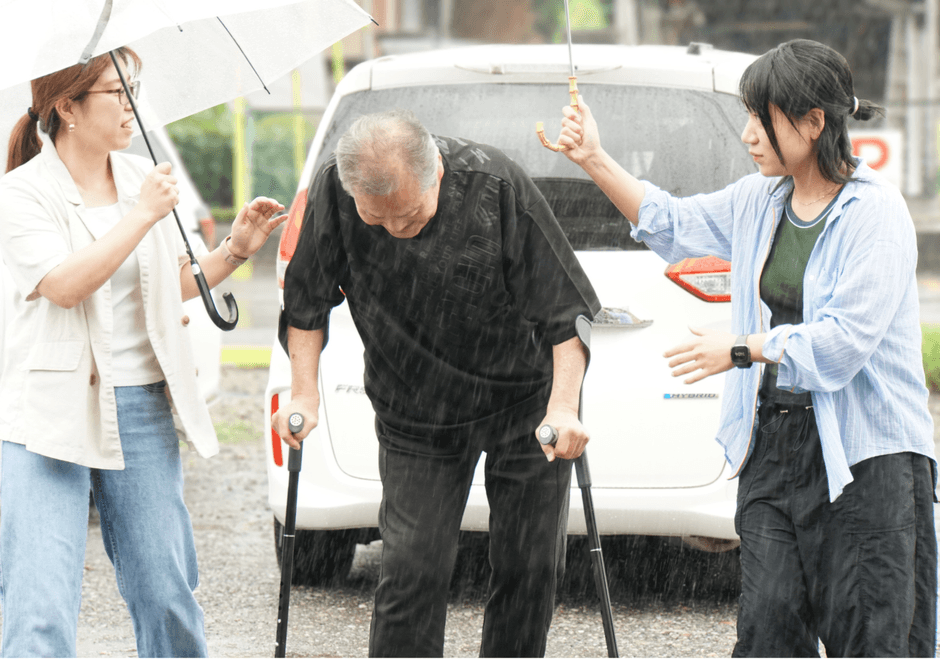 雨の中、杖を使って「いこい」へ。同行したリハビリ職員が傘を差しながら付き添いました。